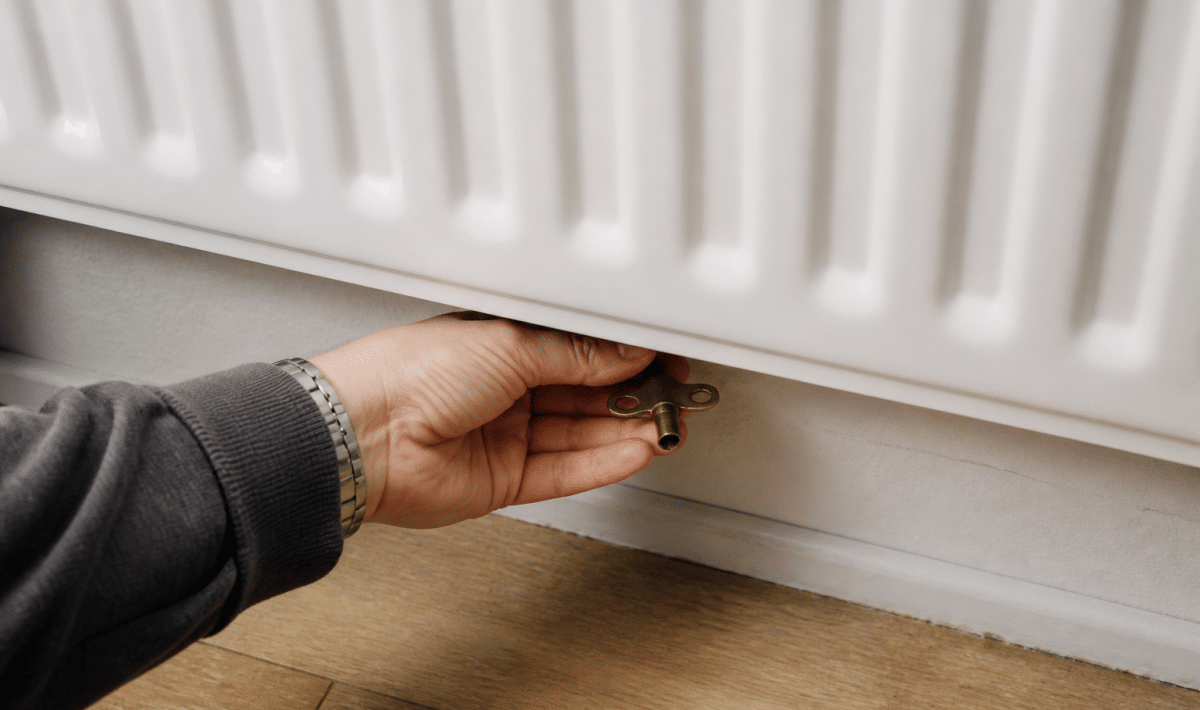 Main tenant une cle sous un radiateur blanc