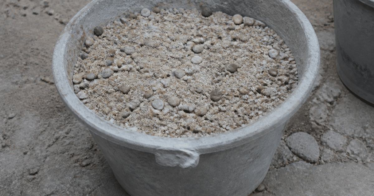 Seau de beton gris contenant sable et graviers melanges