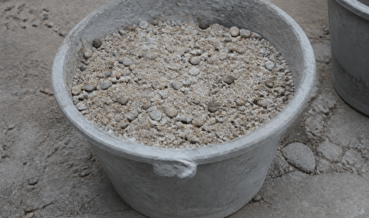 Seau de beton gris contenant sable et graviers melanges